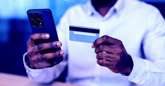 A color-treated photo of a man holding up a phone and a credit card.
