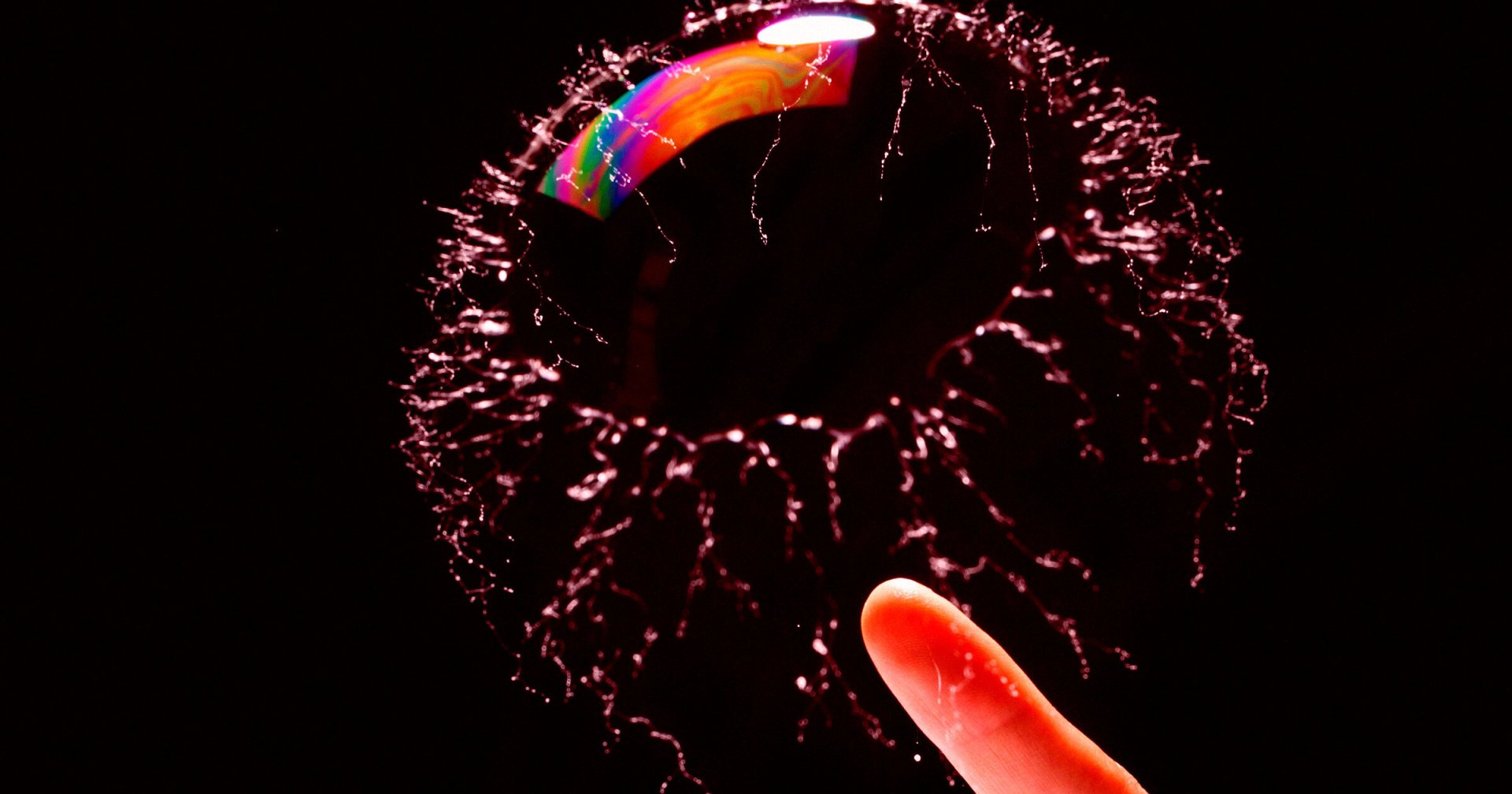 A finger popping a soap bubble.