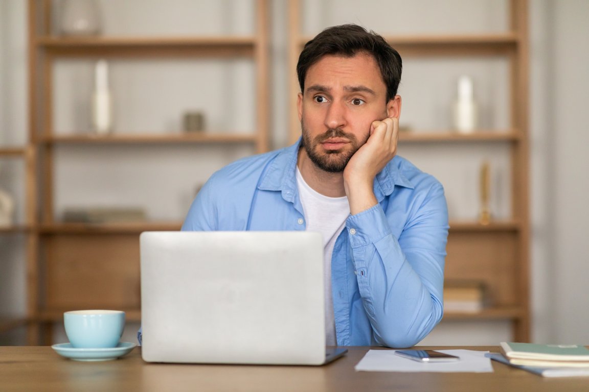 A man is shown at his computer with a blank facial expression.