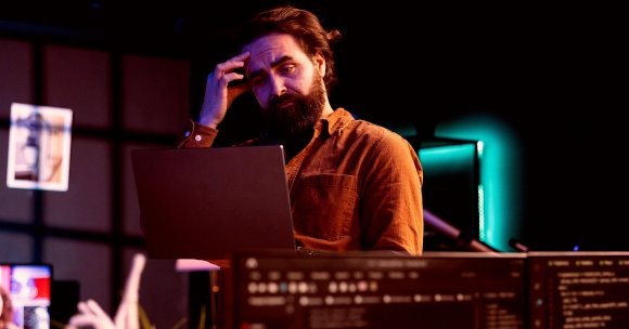 A man looking confused at a laptop.