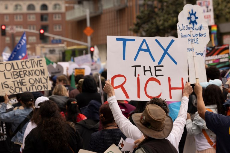 A photo shows a demonstration with a protester bearing a sign that says "Tax the Rich"