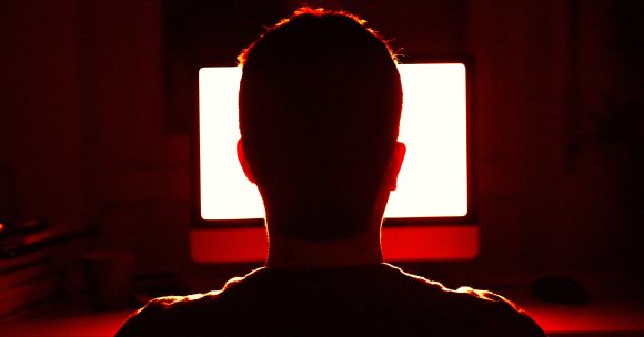 A man looking at a computer screen at night.