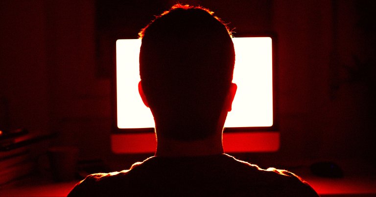 A man looking at a computer screen at night.