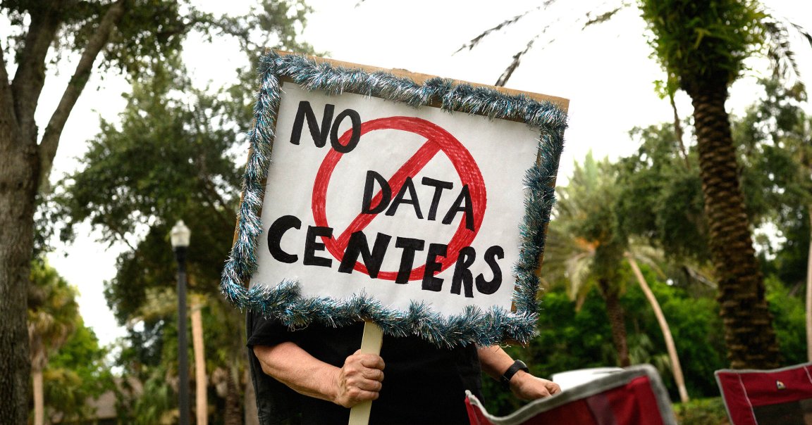 A person holds signs during a nationwide protest against AI data center expansion outside Peace Hall in New Port Richey, Florida. 