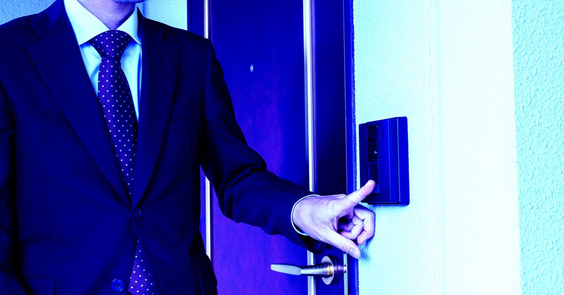 A man in a suit ringing a doorbell.