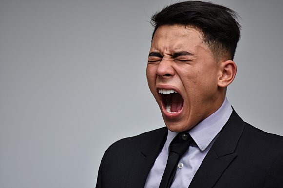 A man in a business suit is shown screaming in frustration
