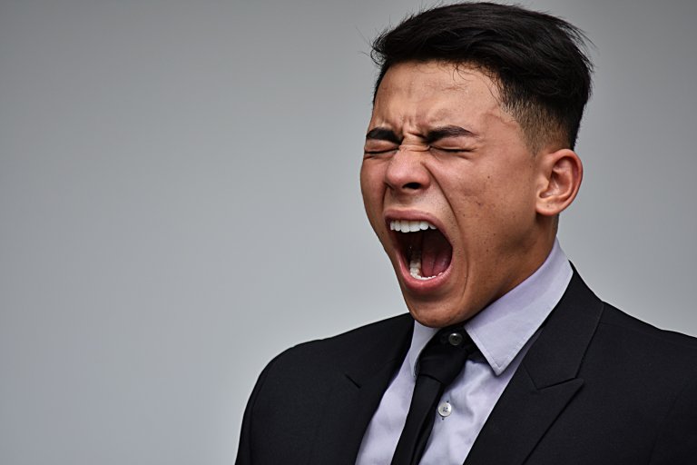 A man in a business suit is shown screaming in frustration
