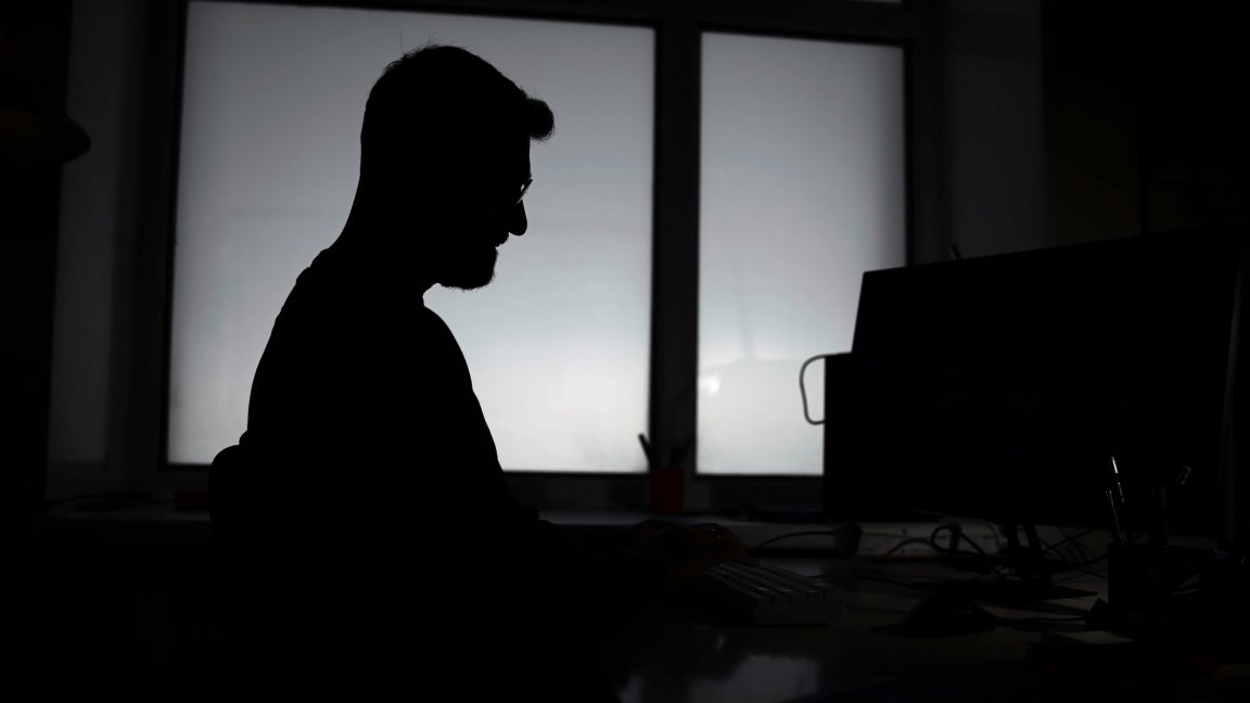 A photo shows the silhouette of a man in darkness.