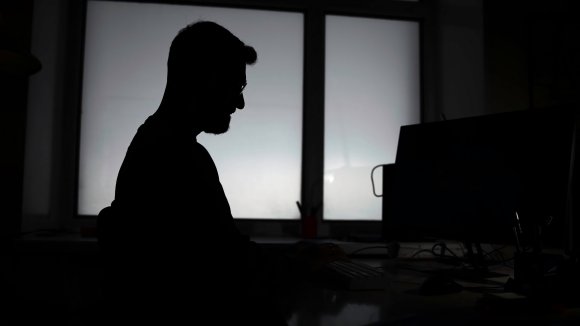 A photo shows the silhouette of a man in darkness.