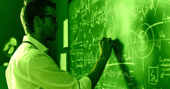 A color-treated photo of a mathematician writing on a blackboard.