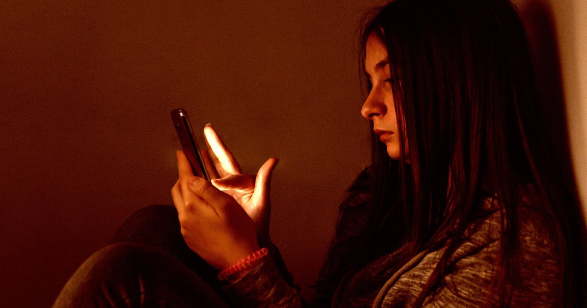 A teen looking at a smartphone screen.