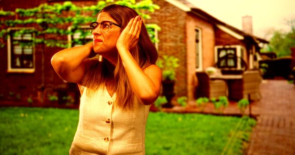A woman holding her ears outside of a house.