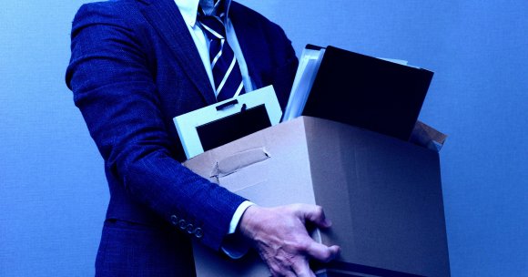 A recently fired man holding his belongings in a box.