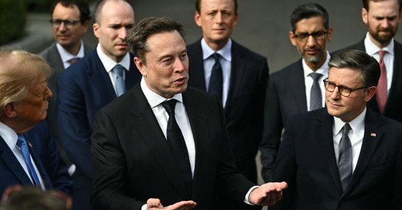 US President Donald Trump and US Speaker of the House Mike Johnson (R) look on as CEO of Tesla and SpaceX Elon Musk speaks to the press.