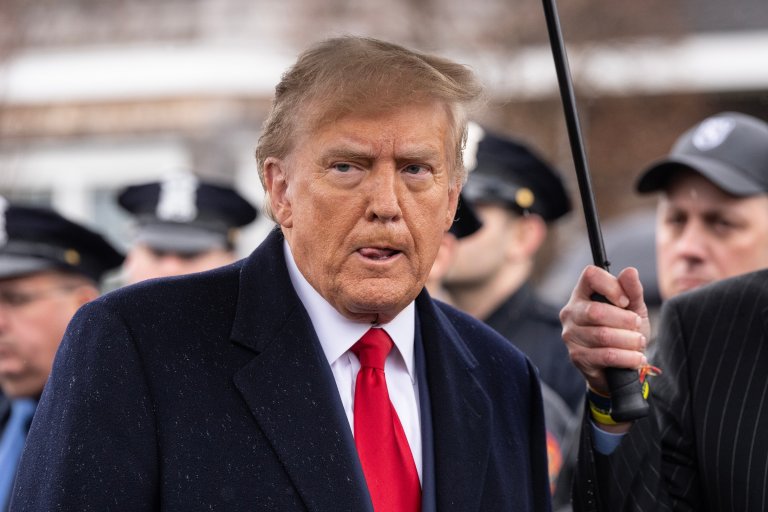 President Trump is shown under an umbrella.