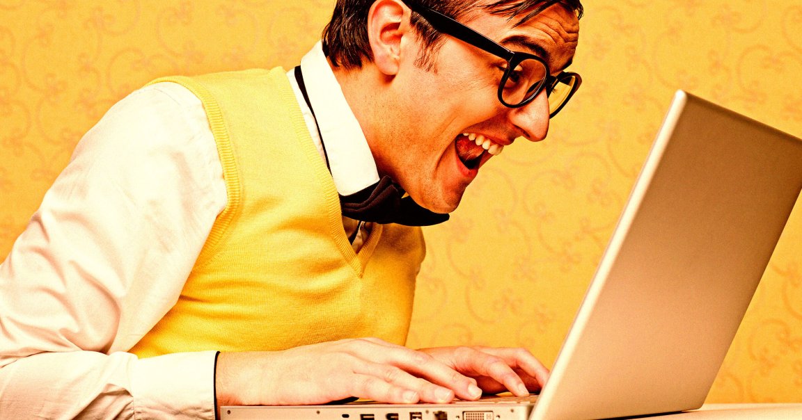 A nerd with glasses staring at an open laptop.