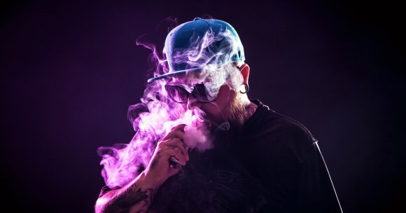A color-treated photo of a man vaping.